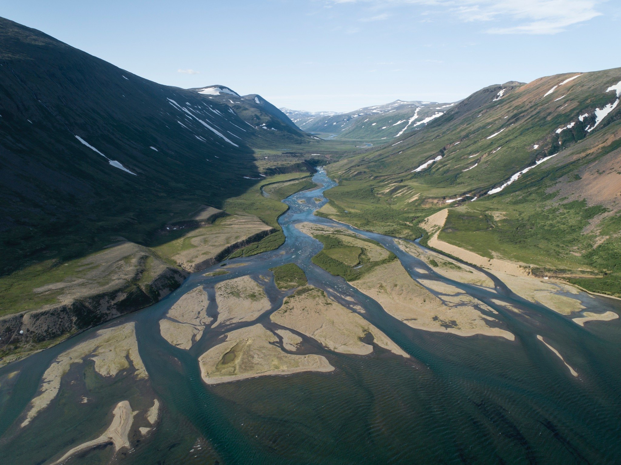 Aerial view of a braided river flowing through a northern mountain valley