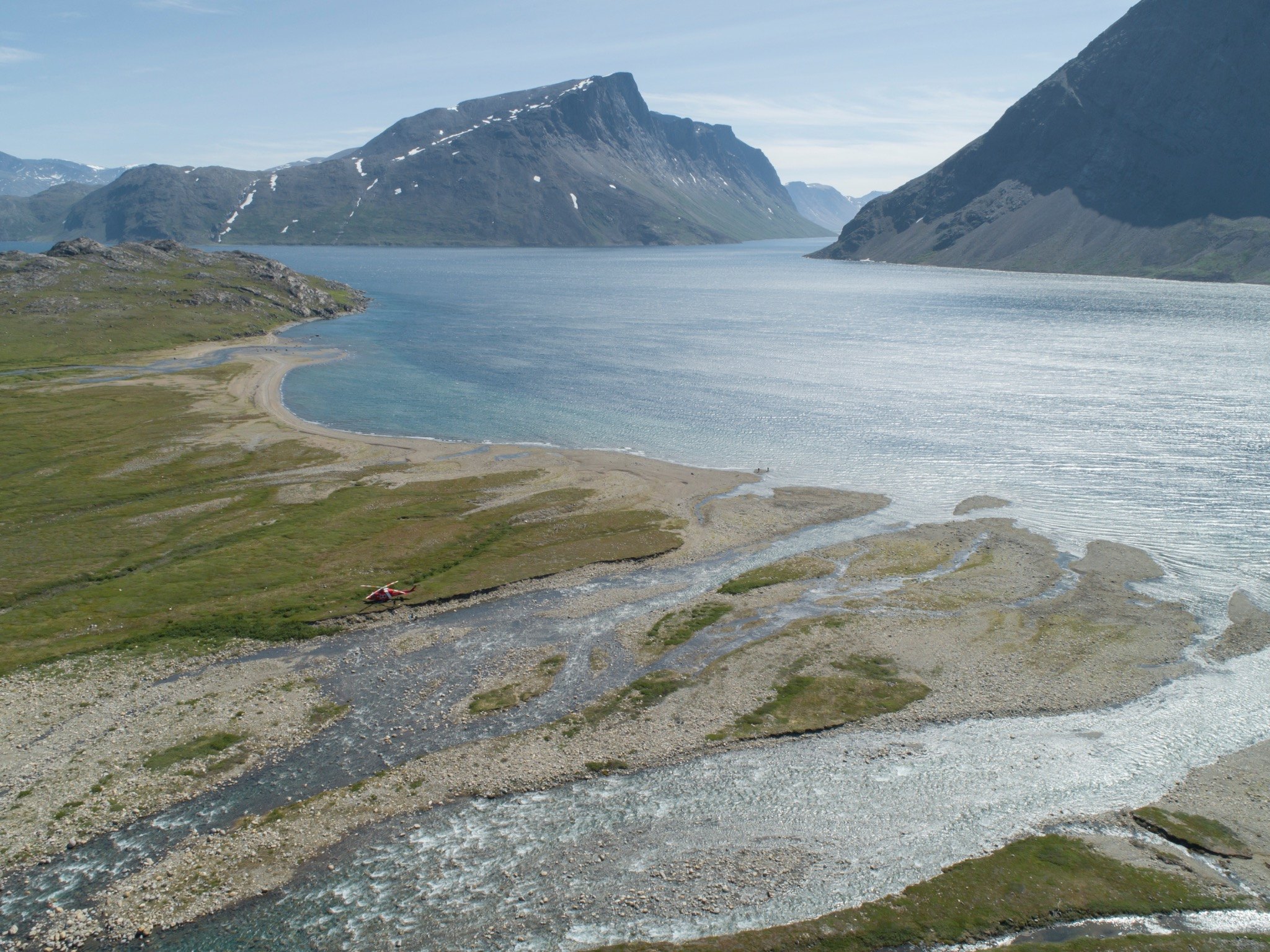 Aerial view of a helicopter beside a river entering a northern fjord